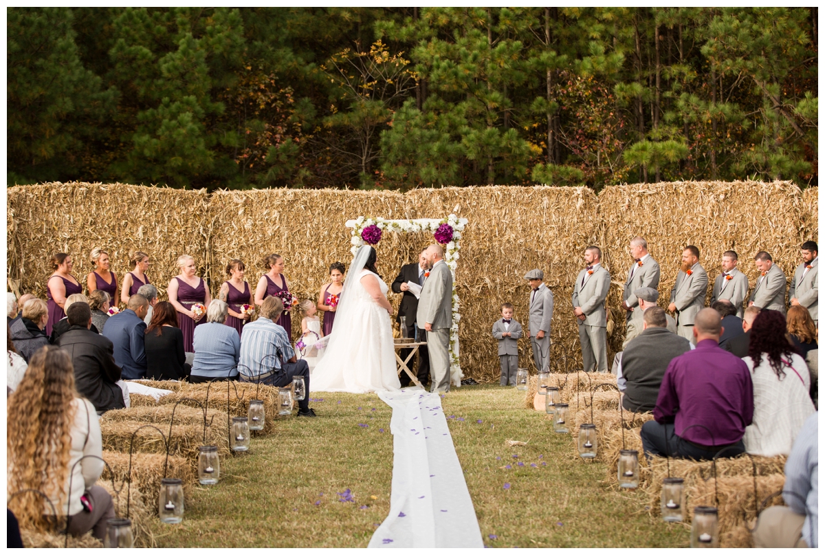 Couple being married in front of a wall of hay bales