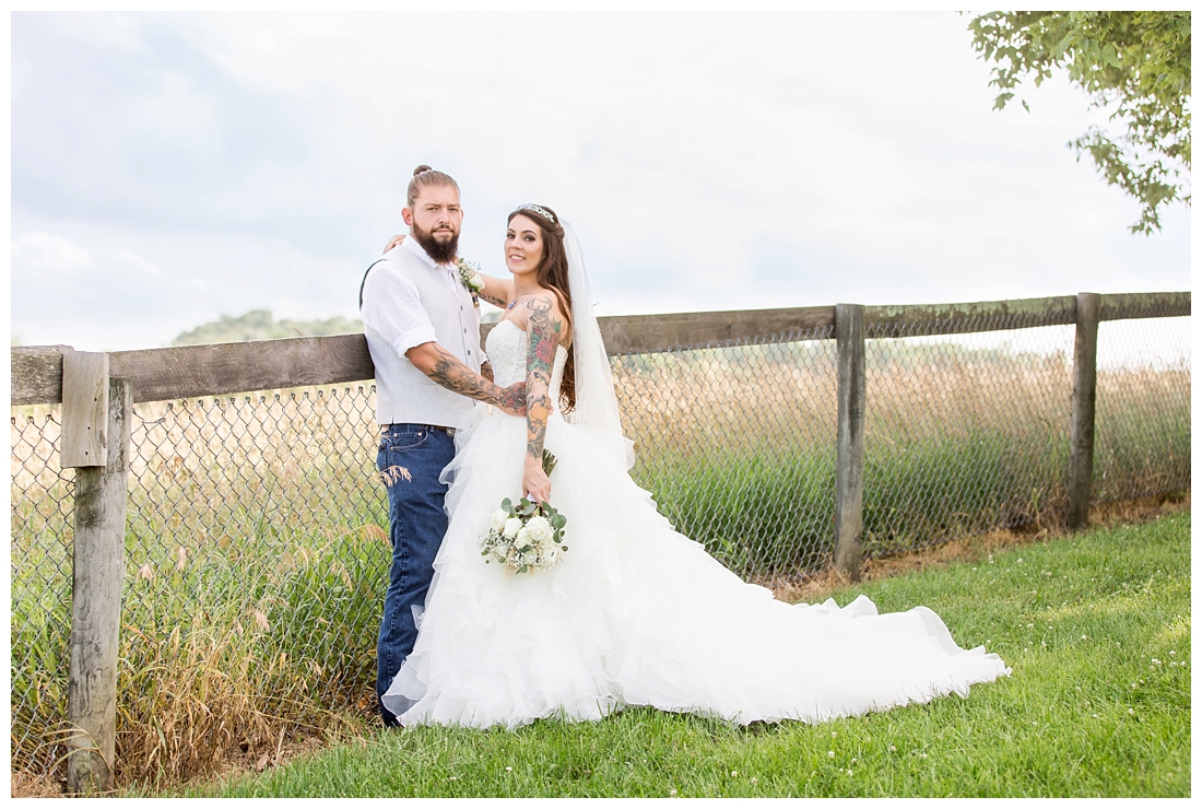 Outdoor bride and groom portraits. Bride and groom against a fence and a field. Maryland wedding at Circle D Farm in Woodbine. Maryland Wedding Photographer.